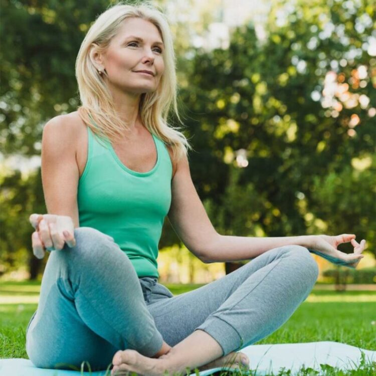 A woman sits cross-legged on a soft patch of grass at Malmo Village,